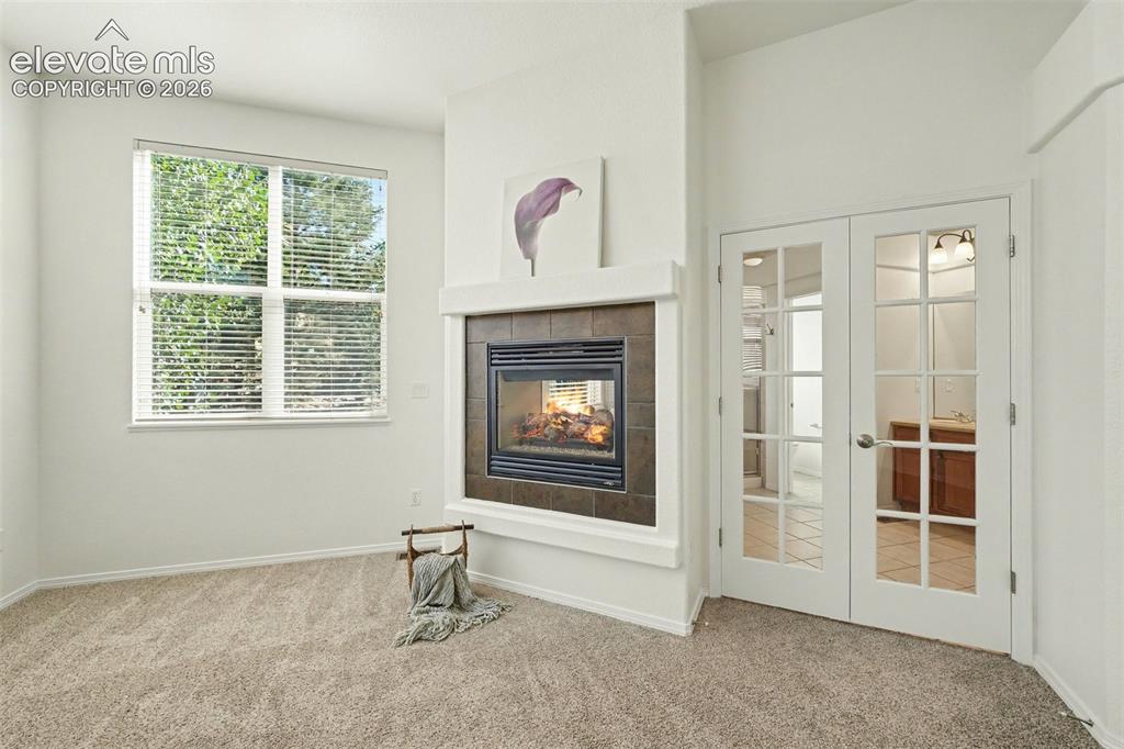 Image 18 of 41: Double sided gas fireplace and glass doors opening to the five-piece primar