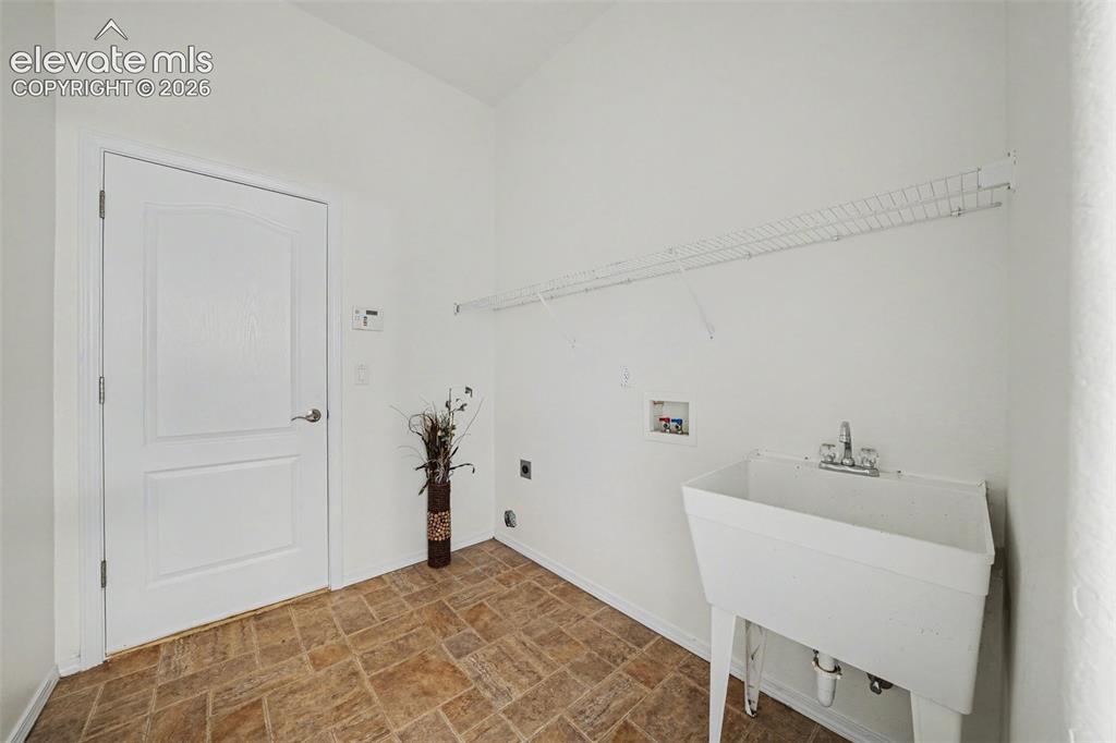 Image 23 of 41: Convenient main-level laundry room with utility sink. The laundry room lead