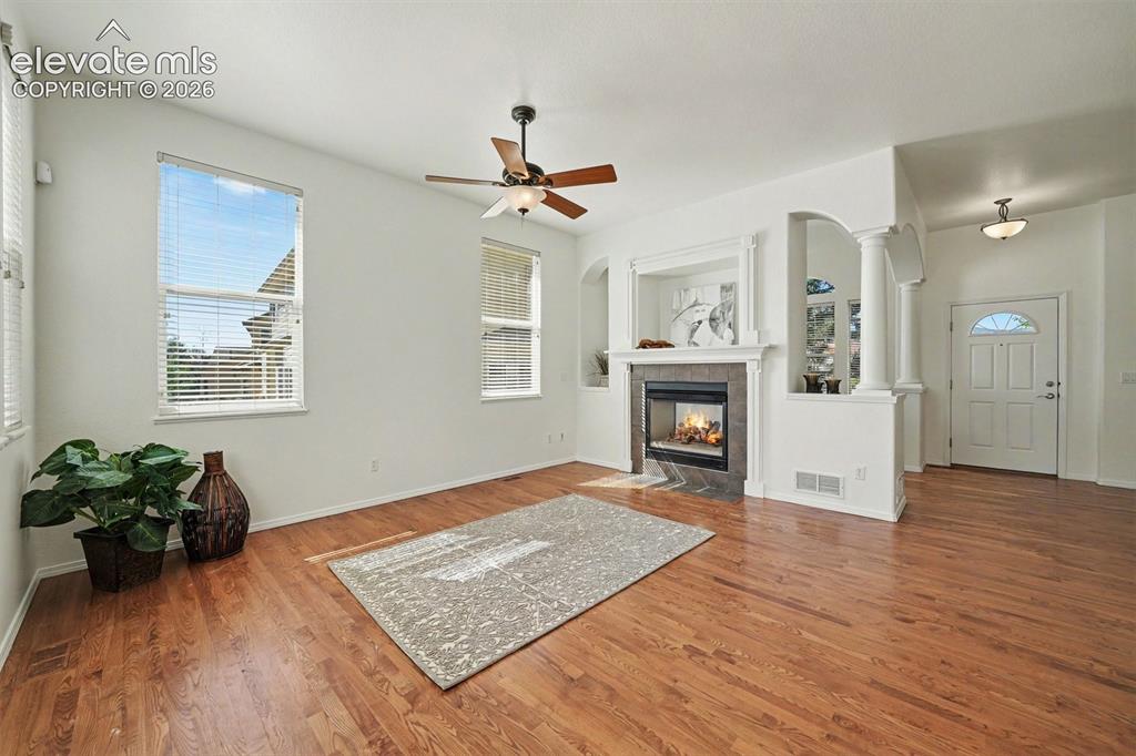 Image 4 of 41: Open living room with double sided fireplace. Formal dining room behind the