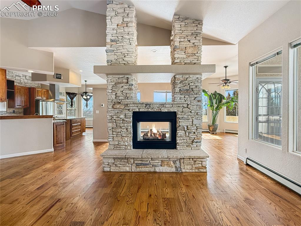 Image 11 of 50: Two way gas fireplace viewed from living room, dining area on the other sid