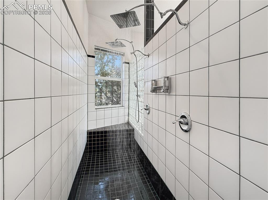 Image 23 of 50: Dual shower heads and a sitting area, spa like