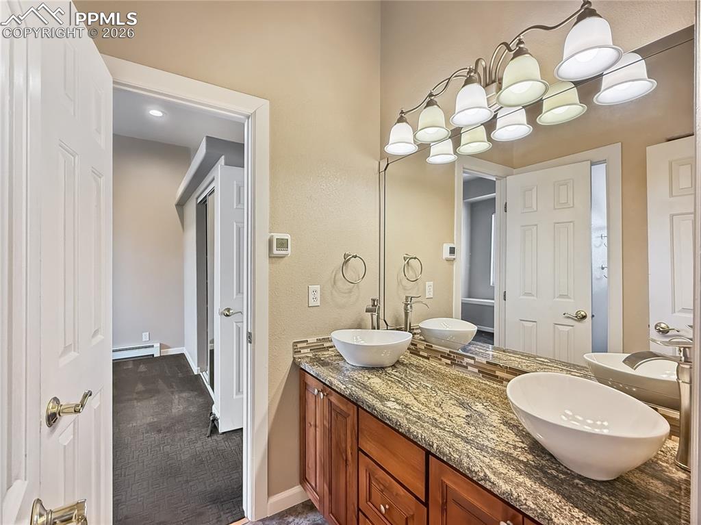 Image 26 of 50: Updated vessel sinks in the jack and jill bath with alder cabinets and gran