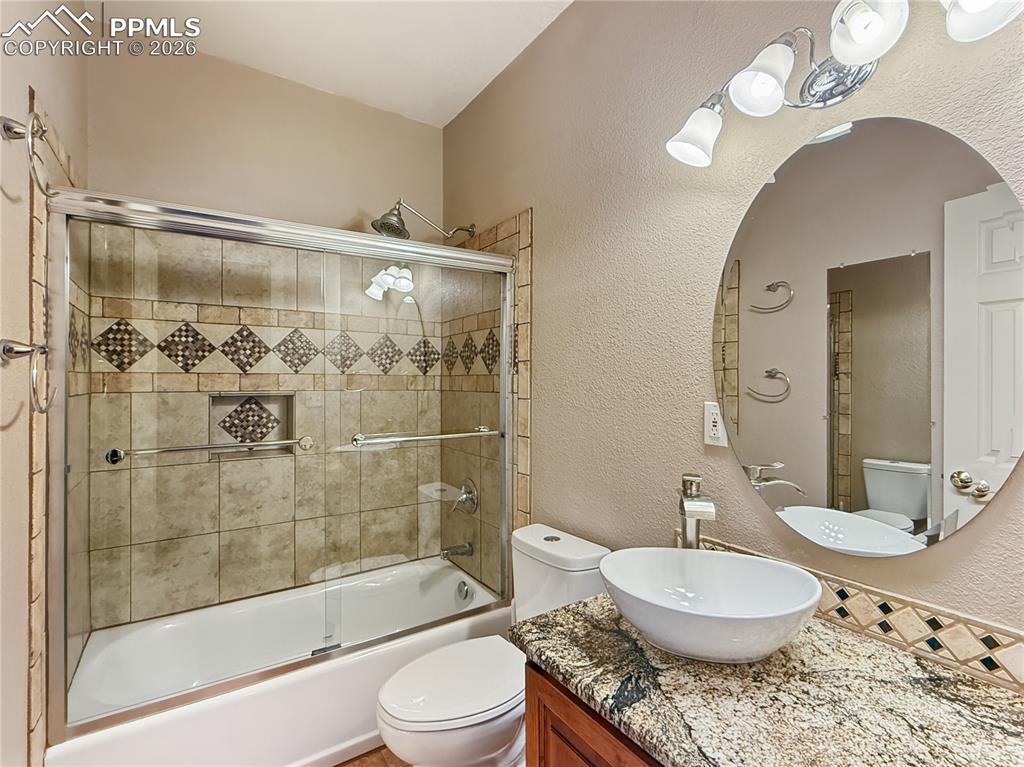 Image 36 of 50: Basement bathroom with vessel sink and granite counters with an alder cabin
