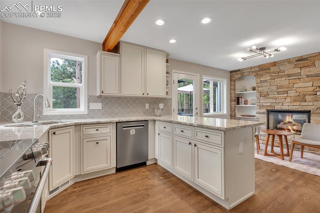Image 12 of 50: Kitchen with a peninsula, dishwasher, light wood-style floors, beamed ceili