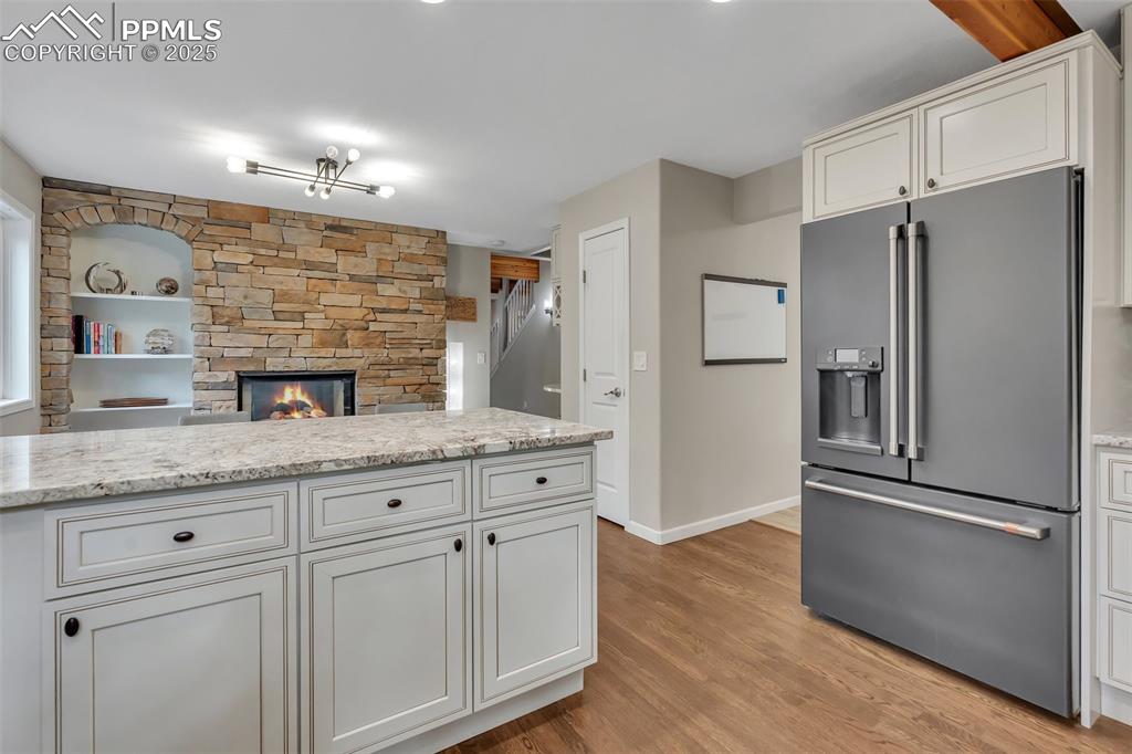 Image 15 of 50: Kitchen featuring high quality fridge, a stone fireplace, light wood-style 