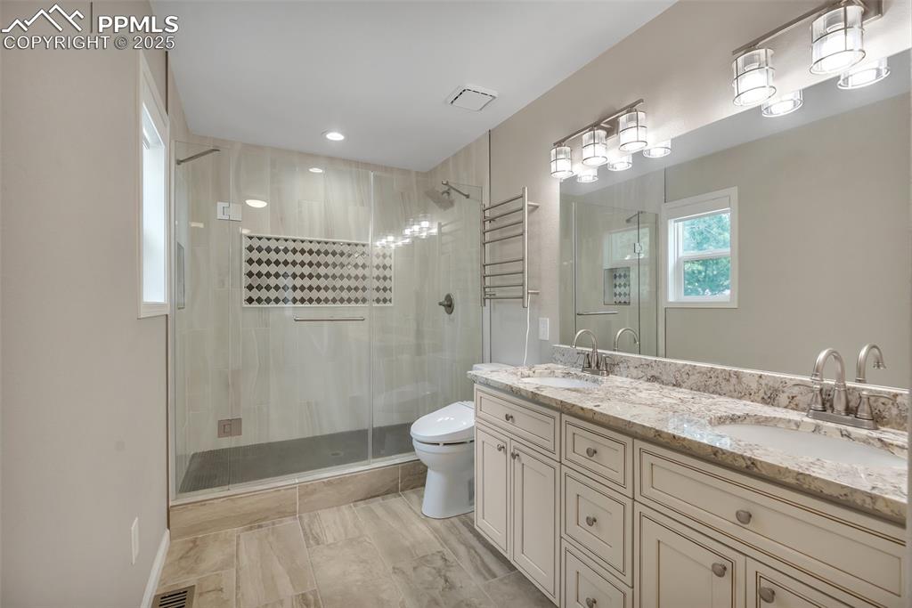 Image 21 of 50: Bathroom with a shower stall and double vanity