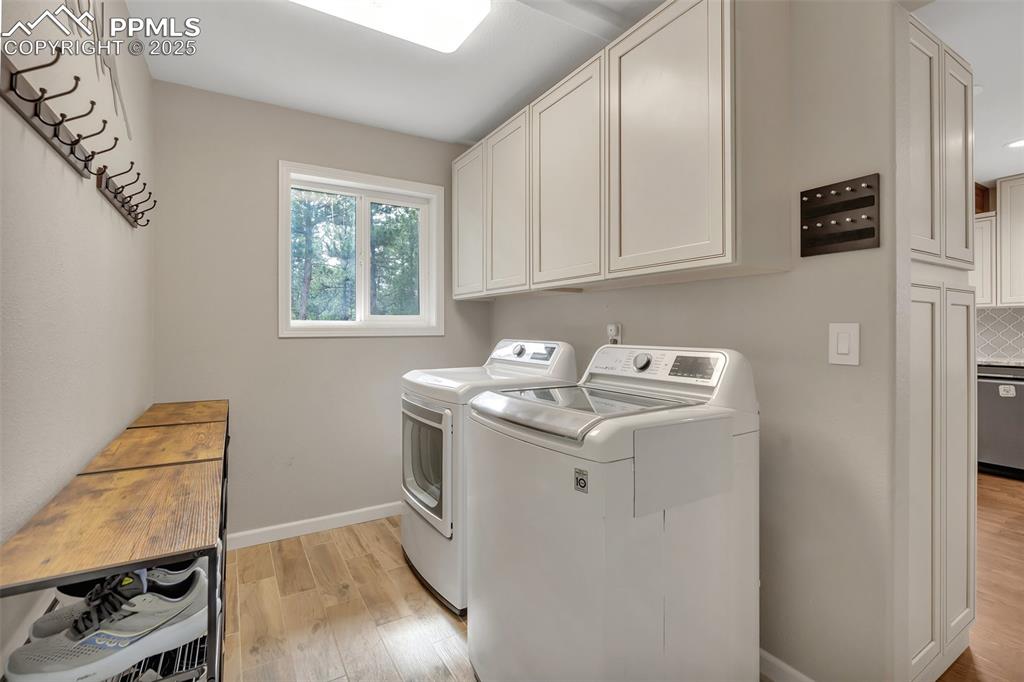 Image 23 of 50: Laundry room with cabinet space, washing machine and dryer, and light wood-