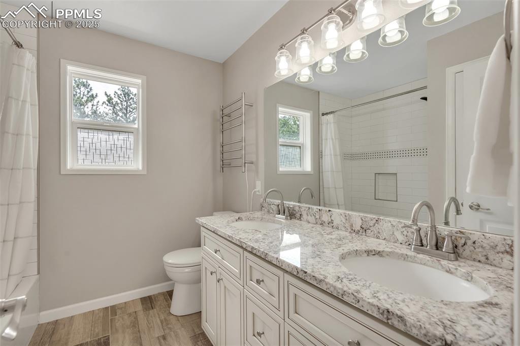 Image 31 of 50: Full bath featuring wood finished floors, double vanity, and shower / batht