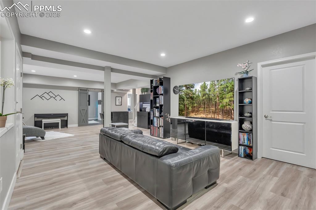 Image 33 of 50: Living area featuring a fireplace, light wood-type flooring, and recessed l
