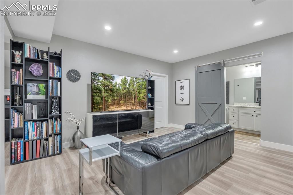 Image 38 of 50: Living area with a barn door, recessed lighting, and light wood-style floor