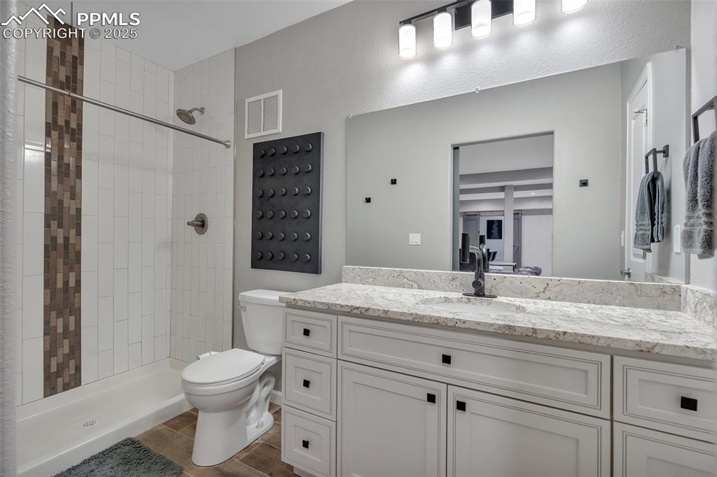 Image 39 of 50: Bathroom featuring vanity, tiled shower, and wood finished floors