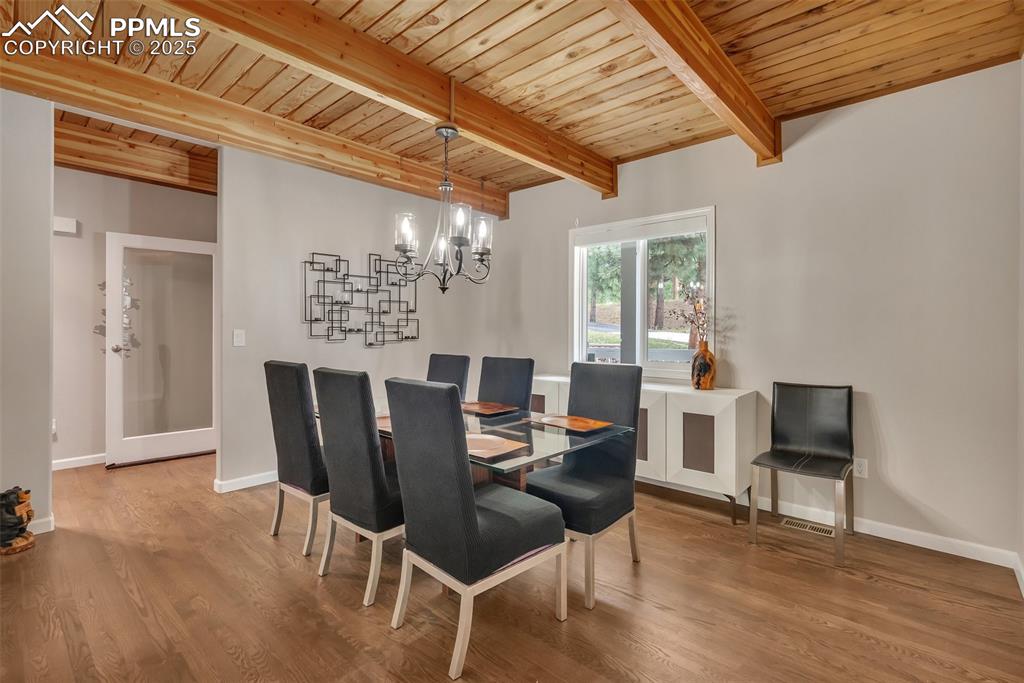 Image 9 of 50: Dining space with a wooden ceiling with exposed beams, a chandelier, and wo