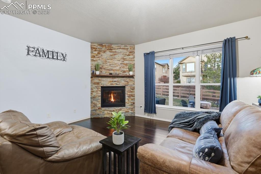 Image 13 of 50: The living room is kept cozy with a corner gas fireplace with a stone surro
