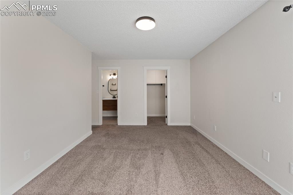 Image 10 of 16: Unfurnished bedroom featuring a spacious closet, carpet, ensuite bathroom,