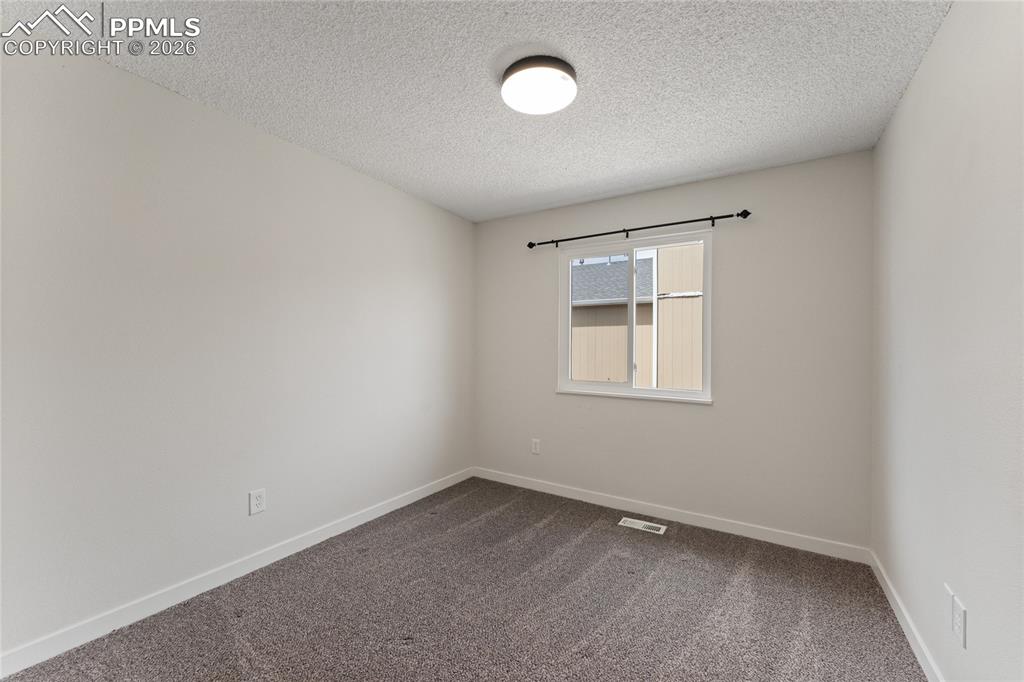 Image 13 of 16: Unfurnished room featuring dark carpet and a textured ceiling