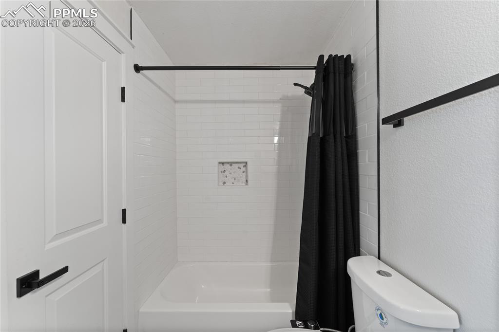 Image 15 of 16: Full bath with a textured wall and shower / bath combo