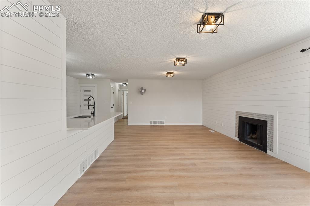 Image 5 of 16: Unfurnished living room with light wood-type flooring, a fireplace, a textu