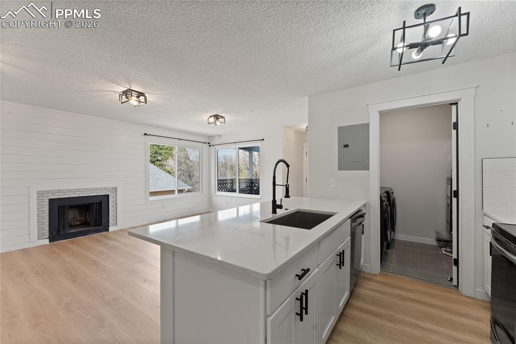 Image 7 of 16: Kitchen with a fireplace, a peninsula, light wood-style flooring, a texture