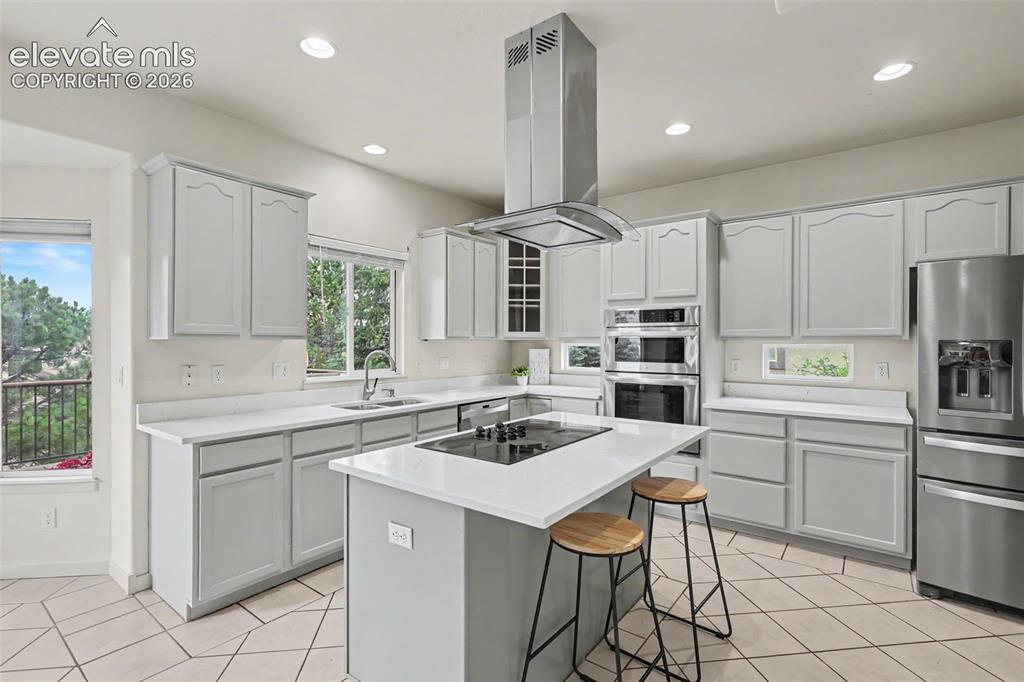 Image 10 of 47: Contemporary kitchen featuring light gray cabinetry, white countertops, sta