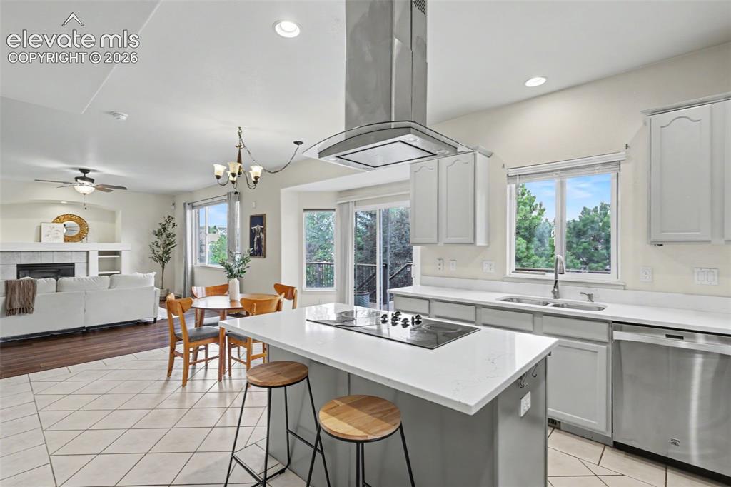 Image 12 of 47: Modern kitchen featuring an island cooktop with overhead range hood, light