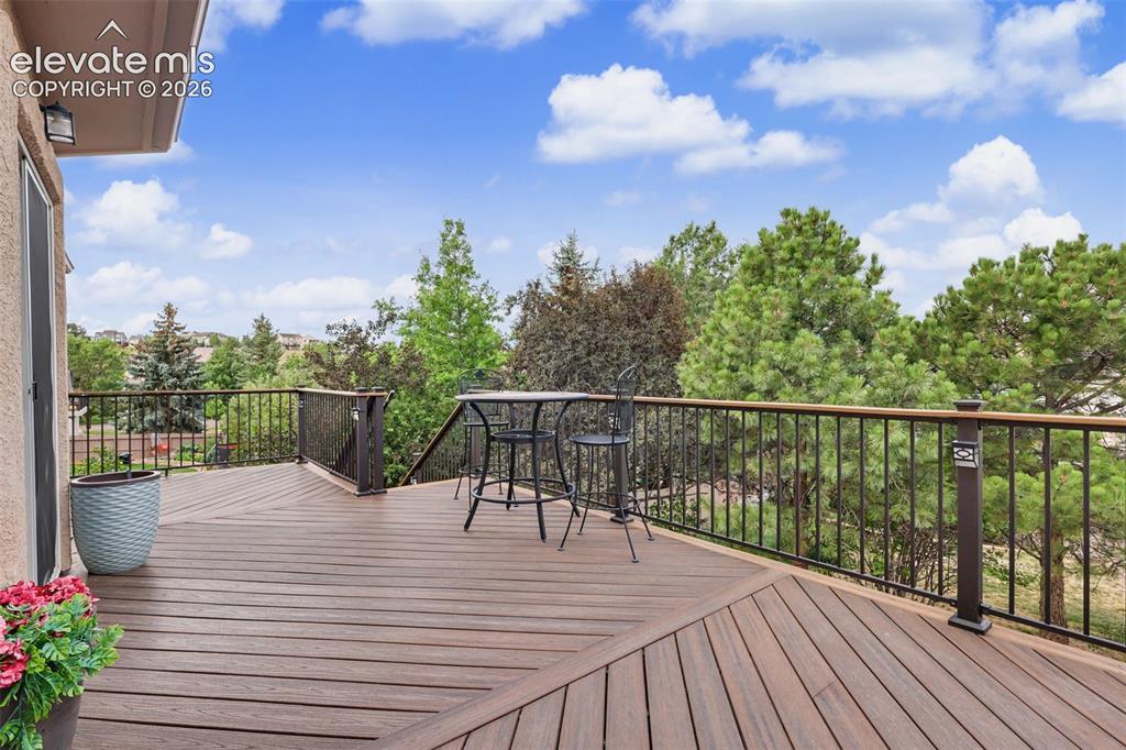 Image 13 of 47: Spacious deck featuring composite decking, dark metal railings, and a natur
