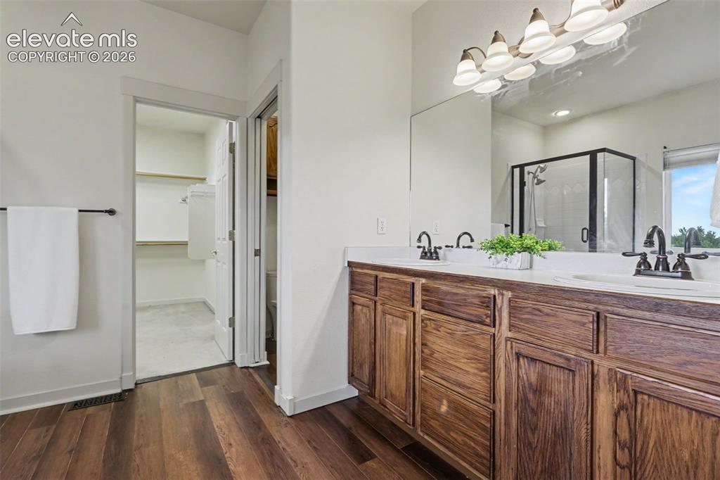 Image 20 of 47: Bathroom featuring a dual vanity with wood-finish cabinetry, white countert