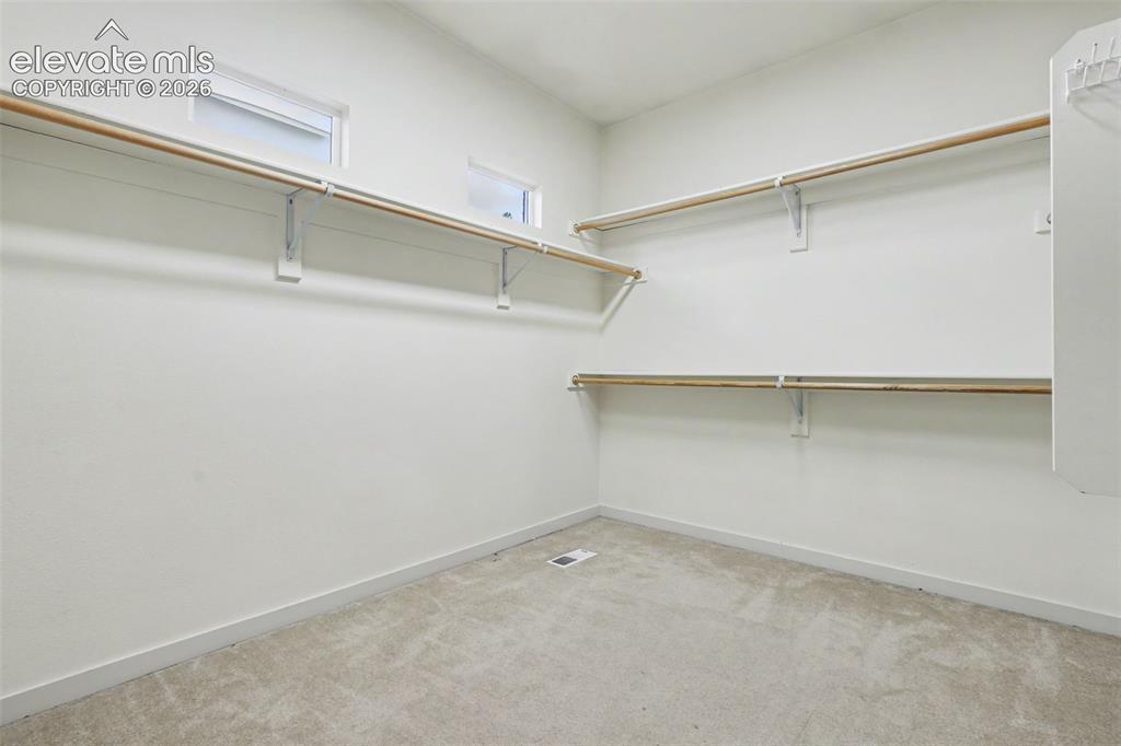 Image 22 of 47: Walk-in closet featuring carpet flooring, crisp white walls, and multiple s