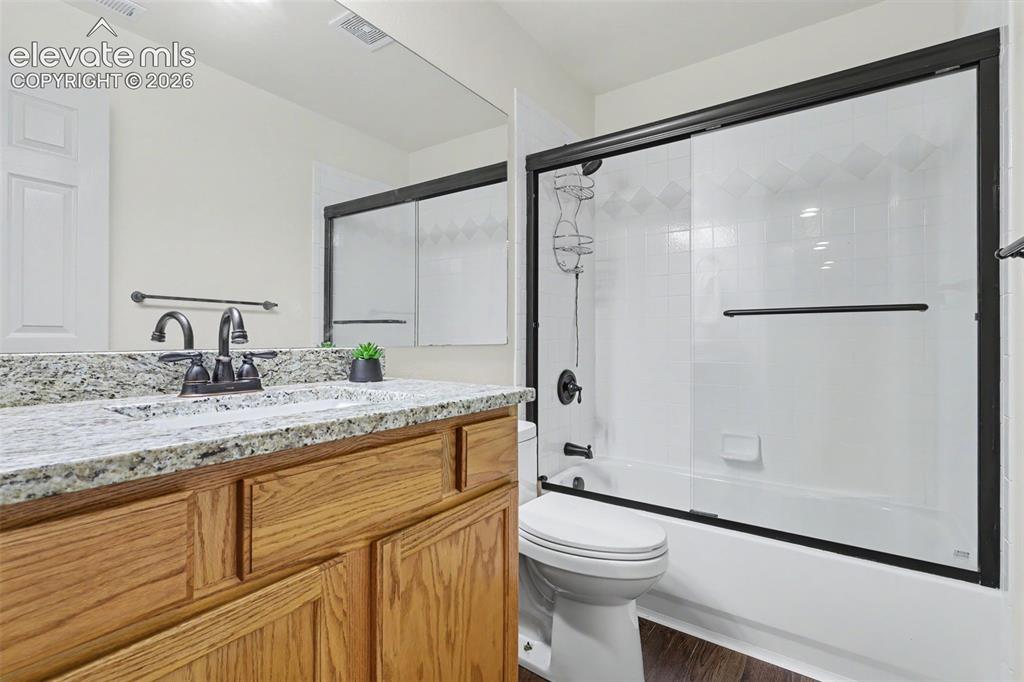 Image 24 of 47: Bathroom featuring a wood-finish vanity with a stone countertop and an unde