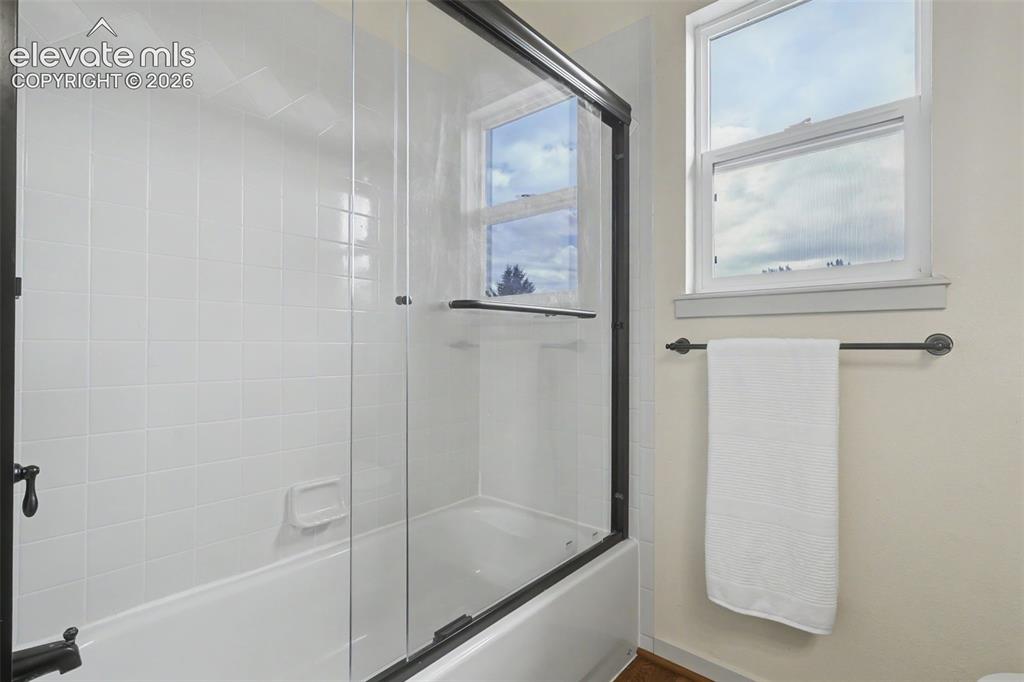 Image 25 of 47: Bathtub-shower combination featuring a clear glass enclosure with dark bron