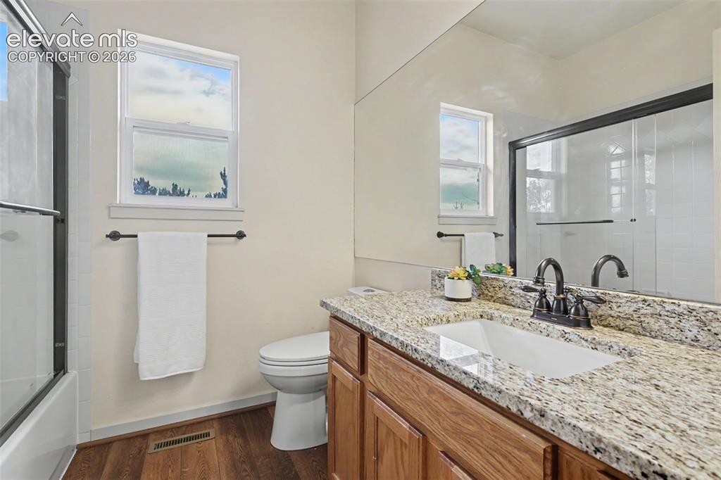 Image 26 of 47: Bathroom featuring a granite-look countertop with an undermount sink, wood-