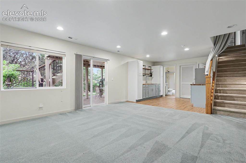 Image 29 of 47: Lower-level living area with light blue carpeting, recessed lighting, and a