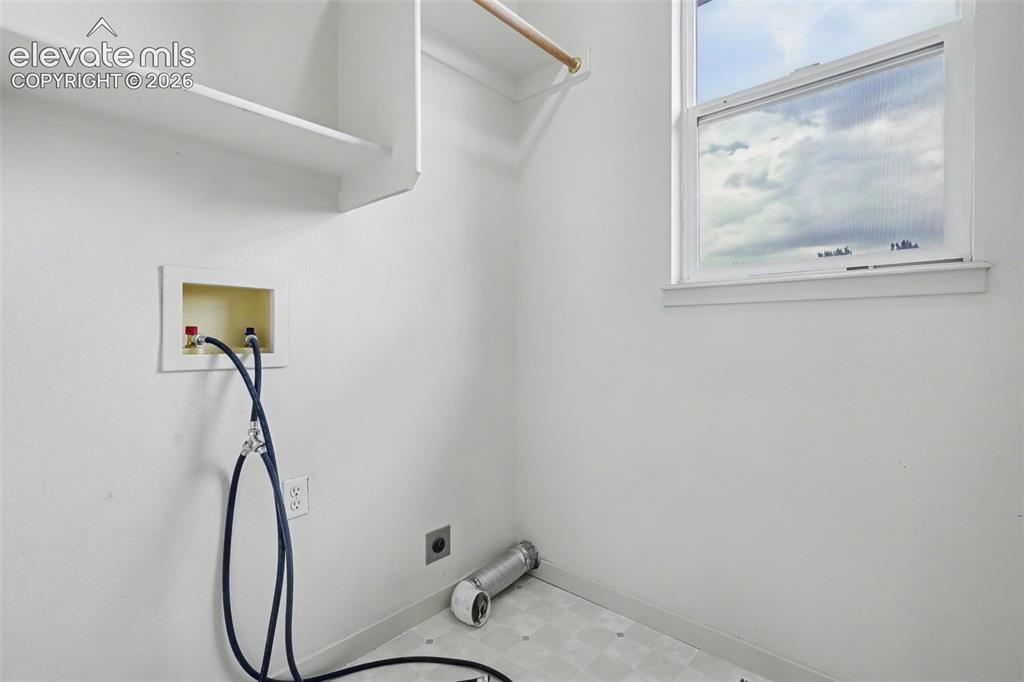 Image 34 of 47: Dedicated utility space featuring a single window, overhead shelving, and a