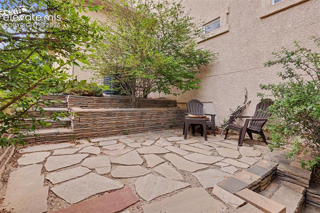 Image 38 of 47: Expansive flagstone patio with tiered stone retaining walls and integrated
