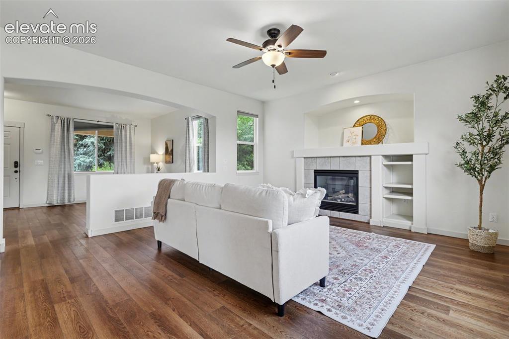 Image 7 of 47: Living area featuring wood-finish flooring, a ceiling fan, and a fireplace