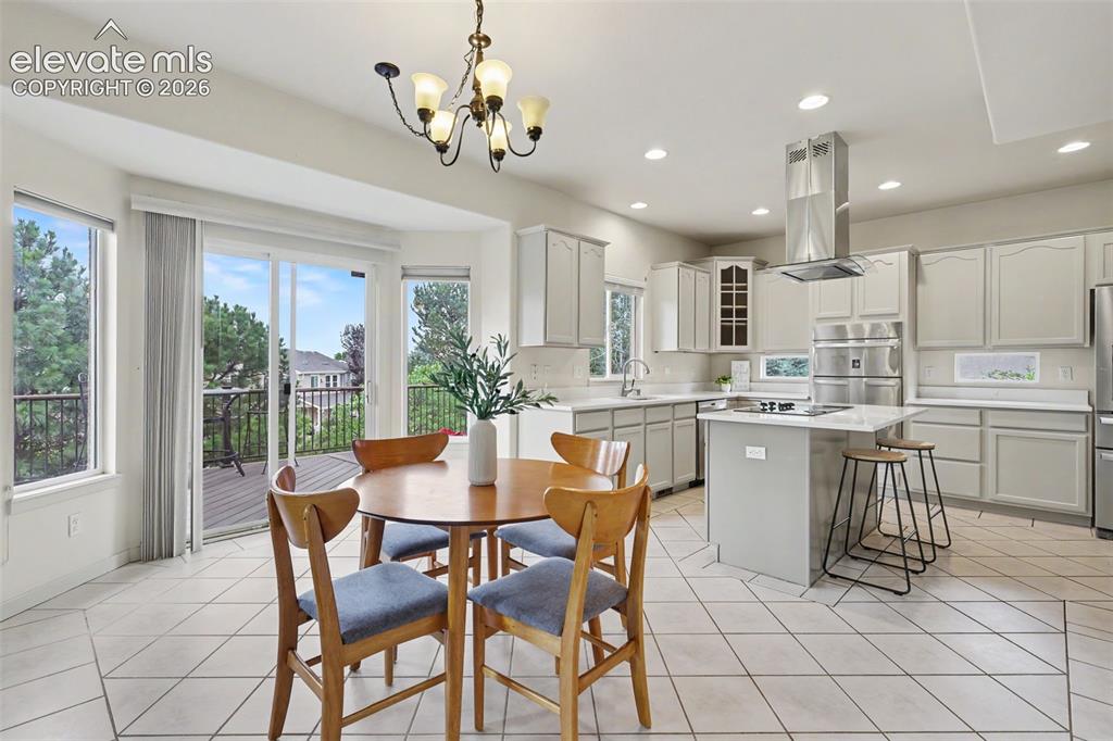 Image 9 of 47: Spacious kitchen and dining area featuring white cabinetry, light counterto