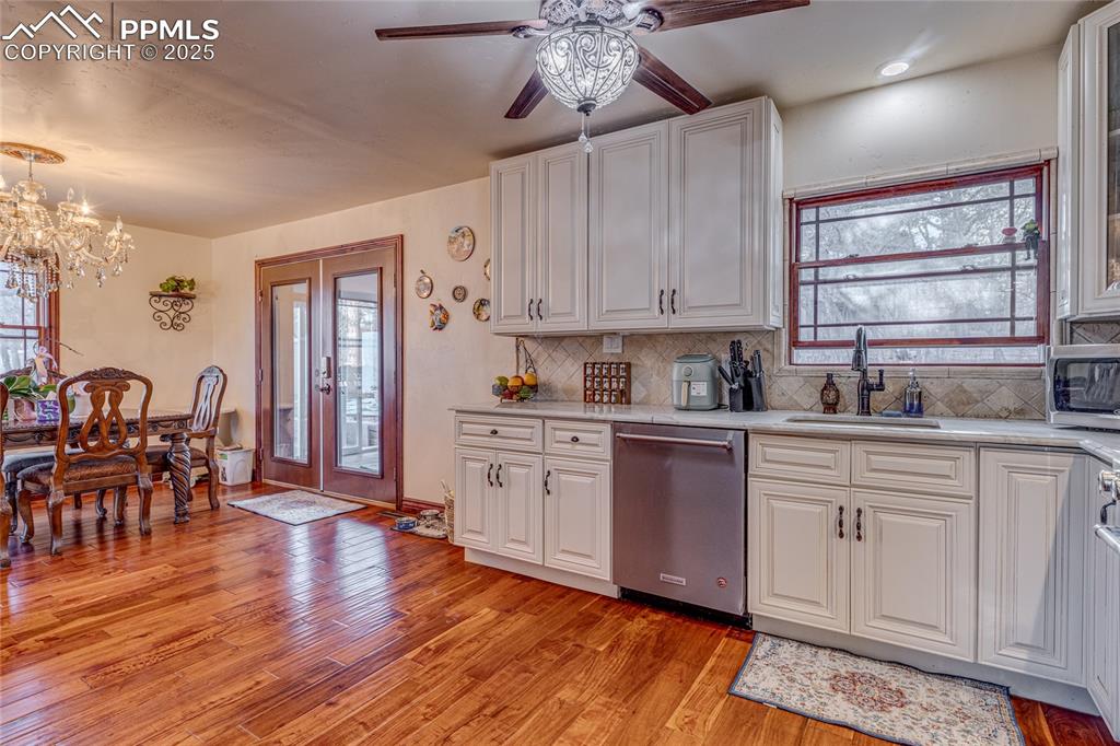 Image 20 of 48: Kitchen with backsplash, sink, dishwasher, light hardwood / wood-style floo