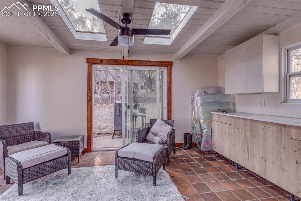Image 38 of 48: Living area with a skylight, ceiling fan, beamed ceiling, and wooden ceilin