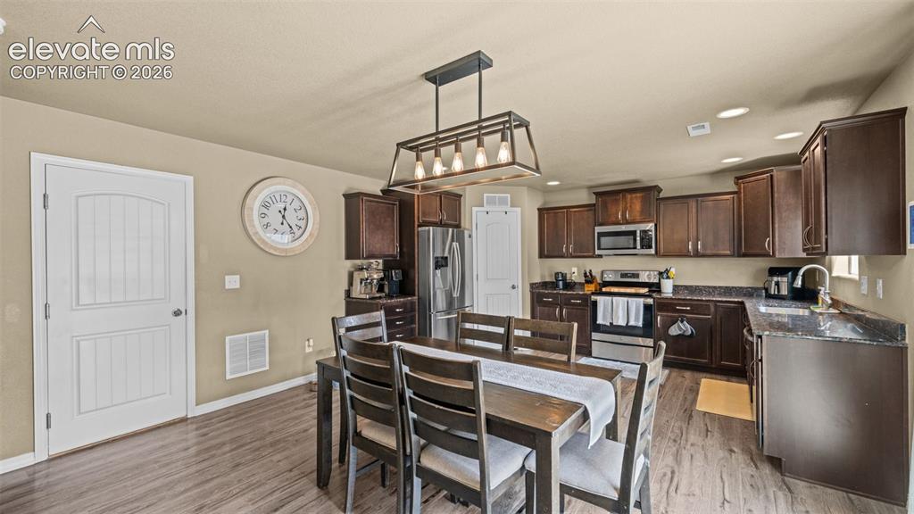 Image 10 of 41: Open-concept kitchen and dining area featuring rich wood-finish cabinetry,