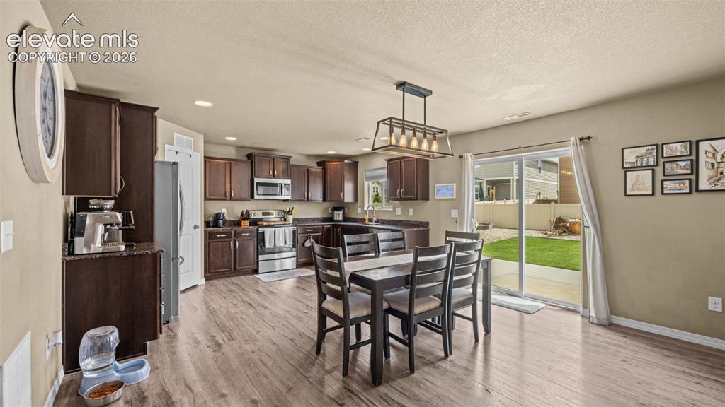 Image 11 of 41: Open-concept kitchen and dining area featuring rich wood cabinetry, stainle