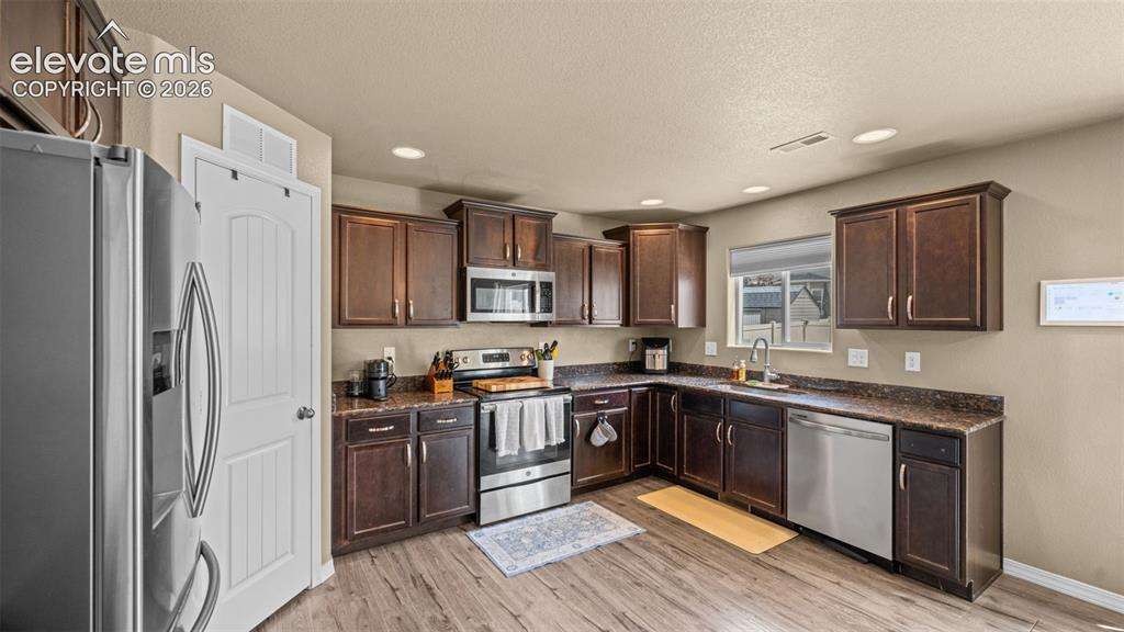 Image 12 of 41: Contemporary kitchen featuring rich wood cabinetry, stainless steel applian