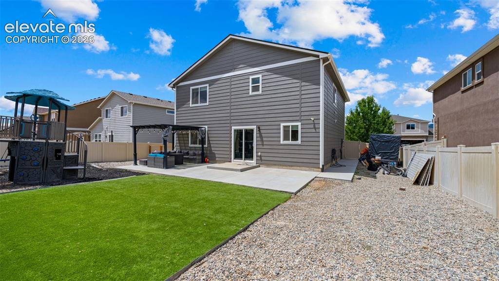 Image 15 of 41: Rear exterior showcasing gray siding with white trim, a concrete patio, and