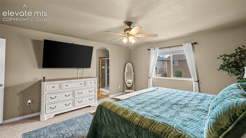 Image 25 of 41: Carpeted bedroom featuring a ceiling fan with light fixture, a window with