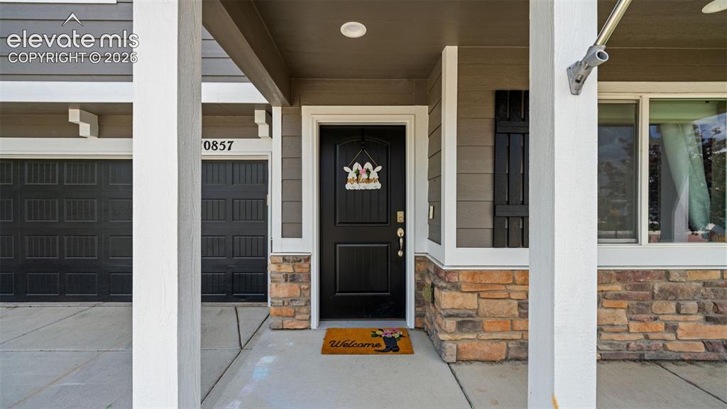 Image 4 of 41: Front entry featuring a dark paneled door, stone accent siding, vertical si