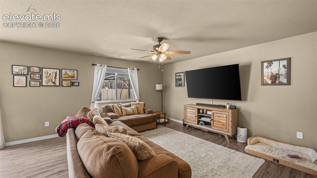 Image 7 of 41: Living area with wood-finish flooring, neutral wall tones, and a ceiling fa