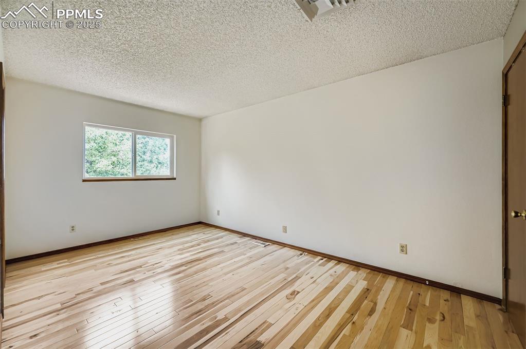 Image 14 of 45: Empty room with light wood-style floors and a textured ceiling