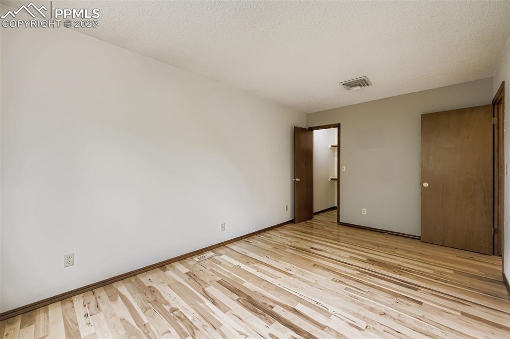 Image 15 of 45: Unfurnished bedroom featuring light wood finished floors and a textured cei