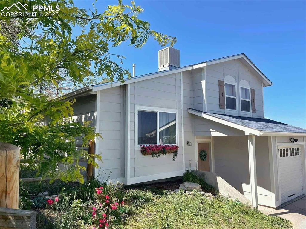 Image 2 of 45: View of front of property featuring an attached garage, a chimney, and roof