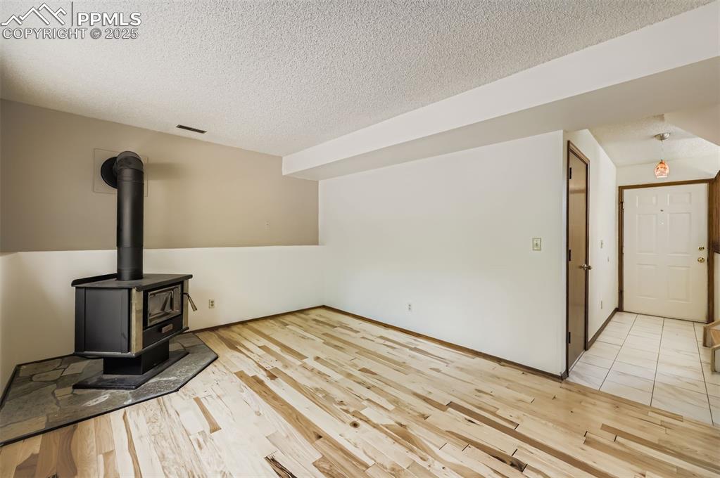 Image 23 of 45: Unfurnished living room with a wood stove, light wood-style flooring, and a