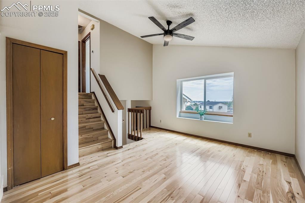 Image 4 of 45: Unfurnished living room featuring lofted ceiling, stairs, light wood-style 