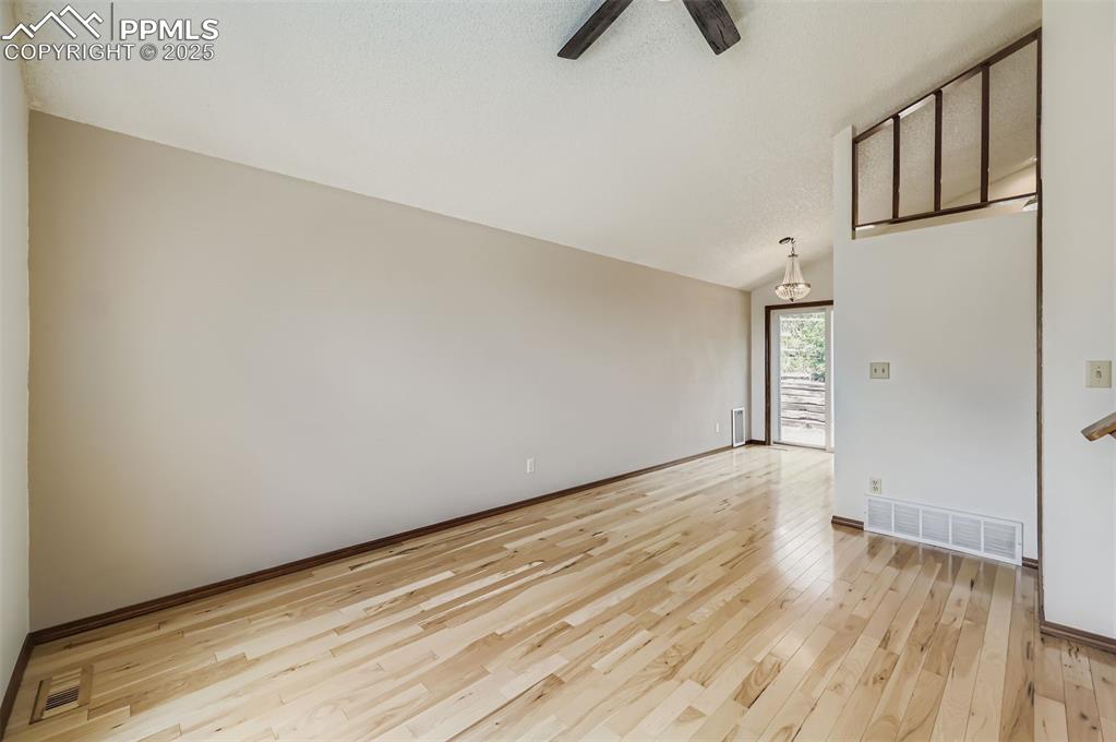 Image 5 of 45: Spare room with light wood finished floors, vaulted ceiling, and ceiling fa